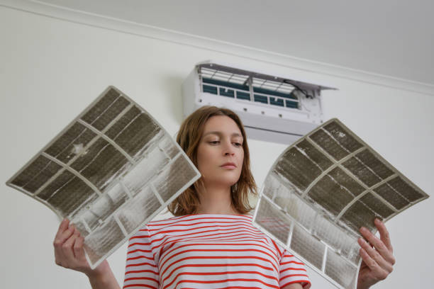 a lady holds 2 dirty air filters 