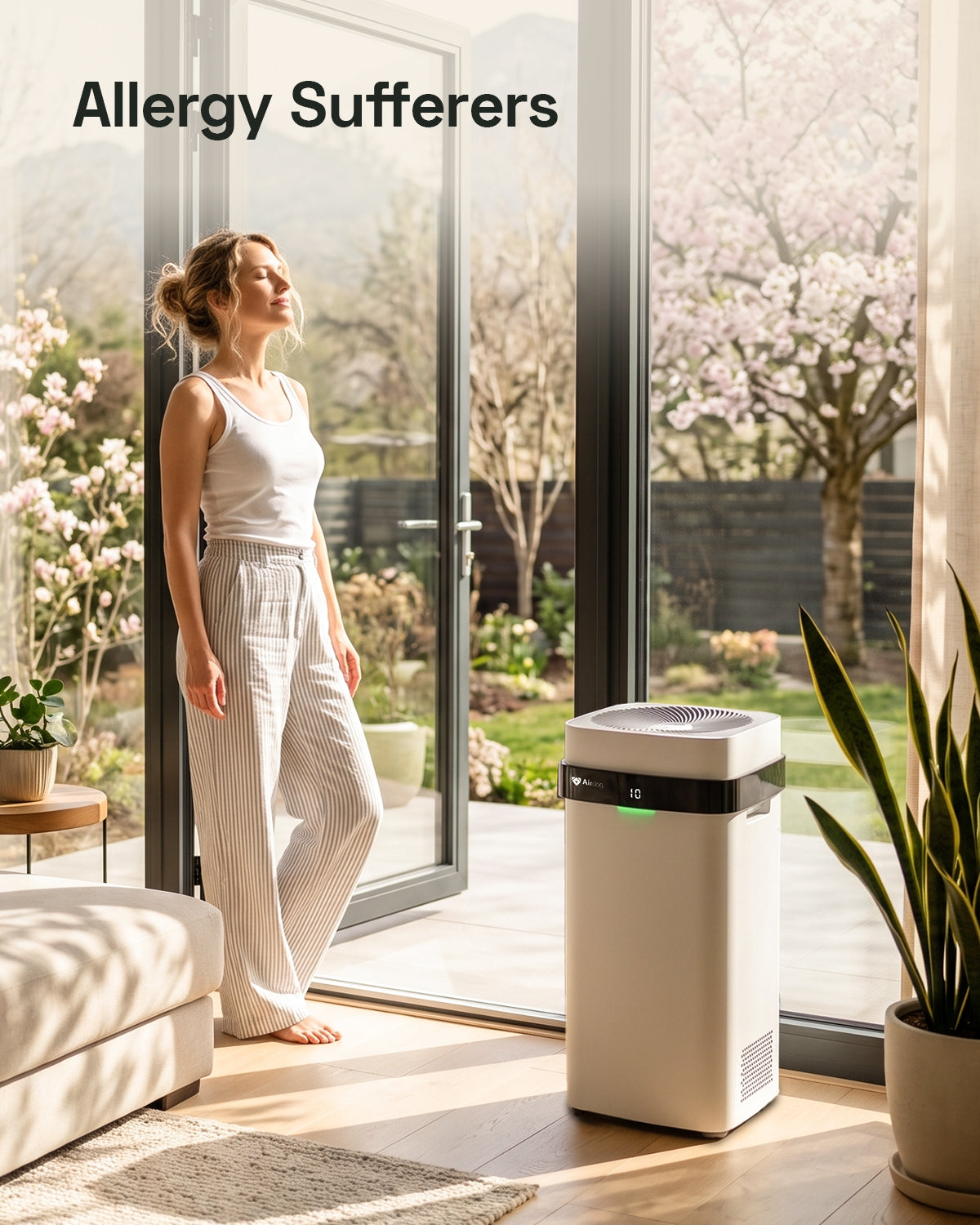 A woman in a white tank top and striped pajama pants stands by open patio doors next to a white and black air Airdog purifier in a bright, modern room. The text 'Allergy Sufferers' is displayed in the upper left corner.